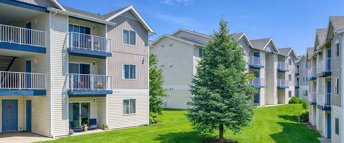 Inviting apartment complex featuring modern balconies, lush green lawns, and scenic views, perfect for a tranquil living experience.