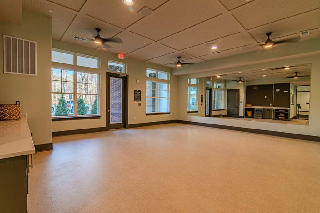 Elegant multipurpose room with large mirrors, ceiling fans, and ample natural light.