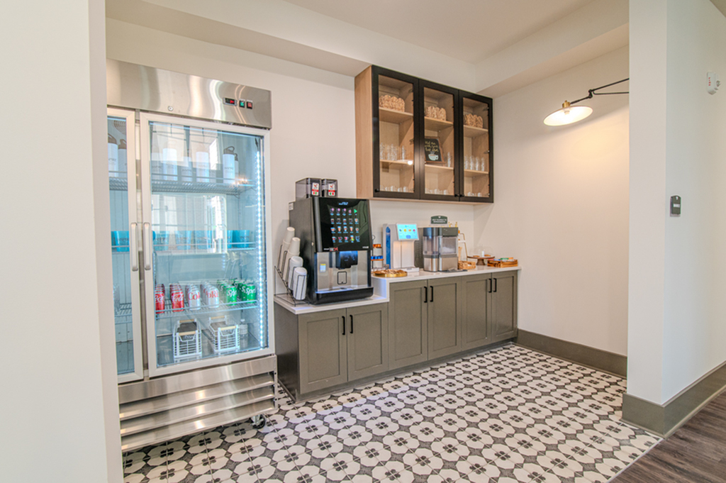 Modern beverage station with a sleek fridge, coffee machine, and elegant cabinetry in a stylish setting.