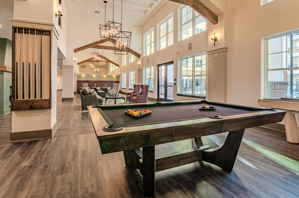 Elegant lounge area featuring a billiards table, stylish seating, and expansive windows enhancing natural light.