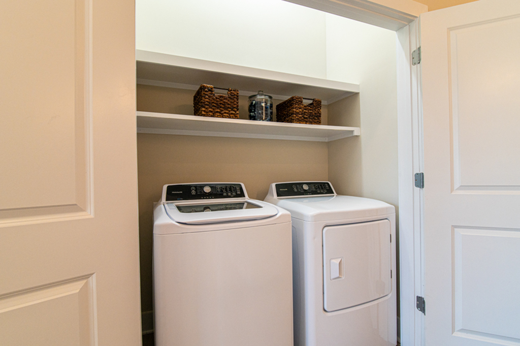 Laundry nook with modern washer, dryer, and shelving in a compact space.