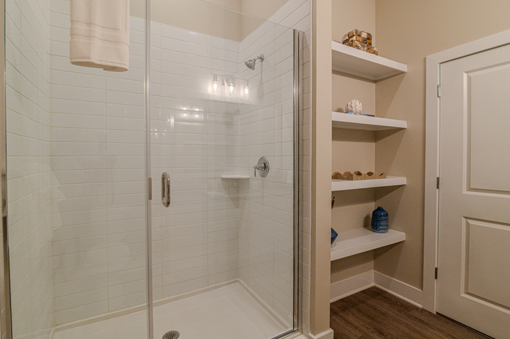 Luxurious bathroom featuring a sleek glass shower with white subway tiles and stylish built-in shelving.