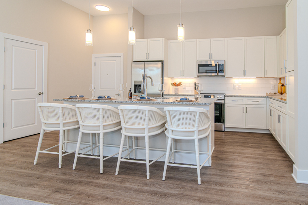 Bright modern kitchen with a large island, stylish lighting, and contemporary white cabinetry.