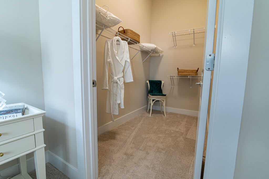 Chic walk-in closet with ample shelving, a plush carpet, and a robe hanging elegantly.