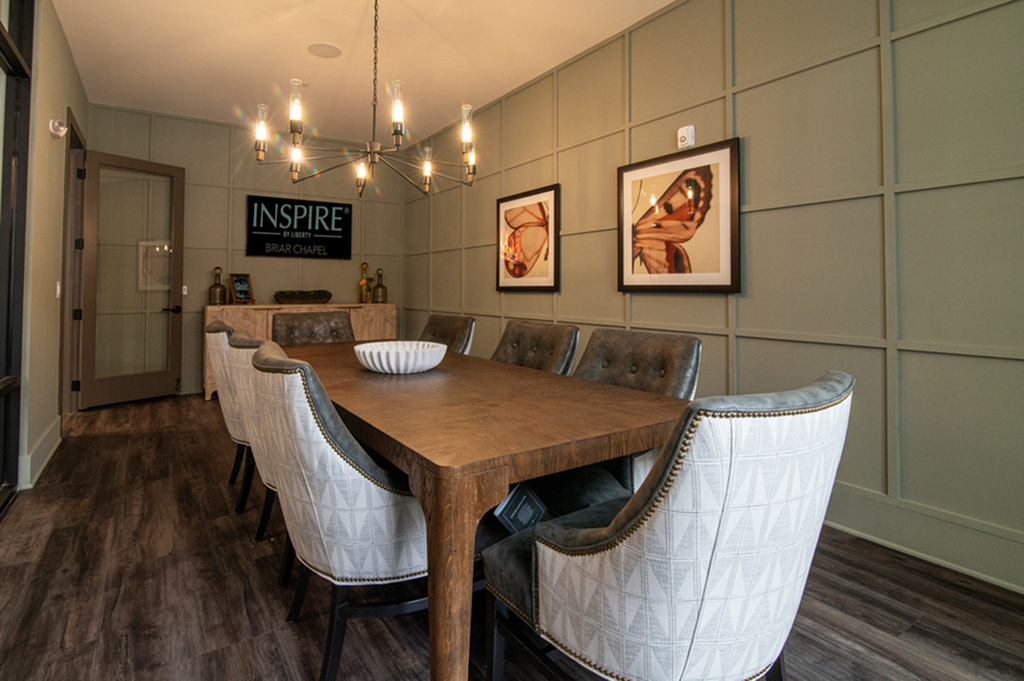 Chic dining room with a wooden table, upholstered chairs, modern chandelier, and artistic wall decor.