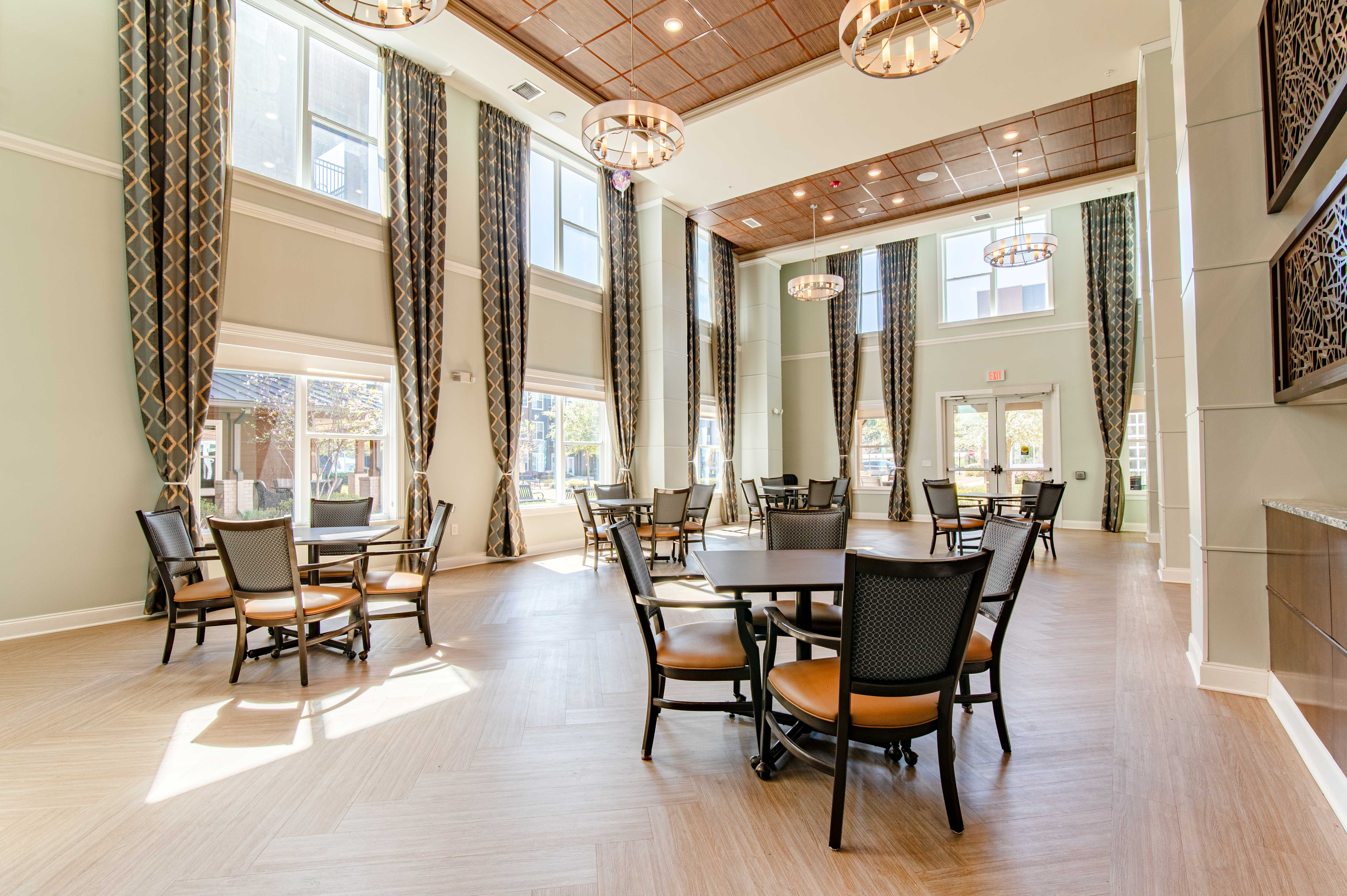 Elegant community room with high ceilings, large windows, and modern decor, featuring multiple seating areas and stylish lighting fixtures.