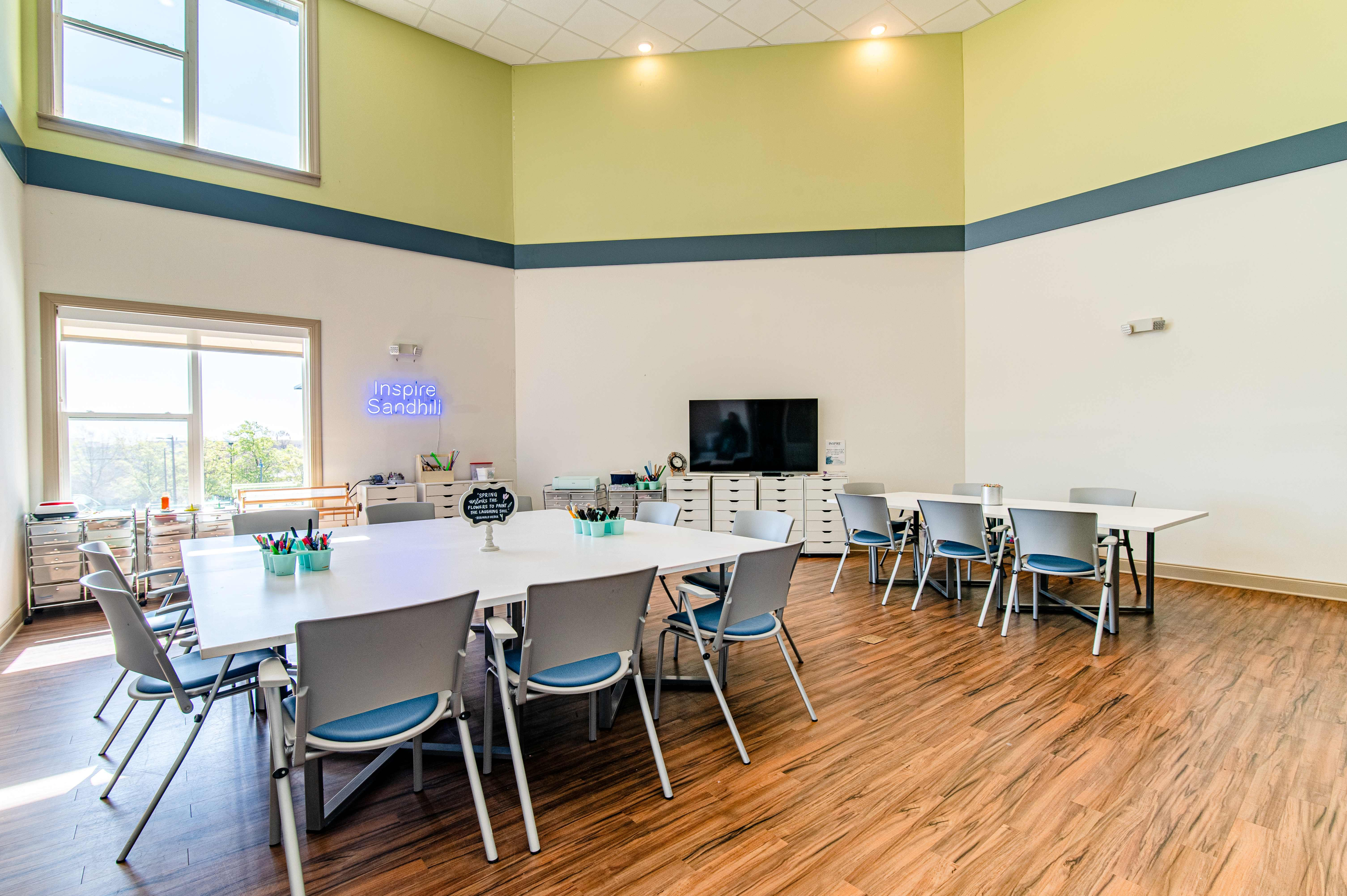 Bright and inviting multipurpose room with high ceilings, natural wood flooring, and modern furniture, perfect for collaborative work and learning.