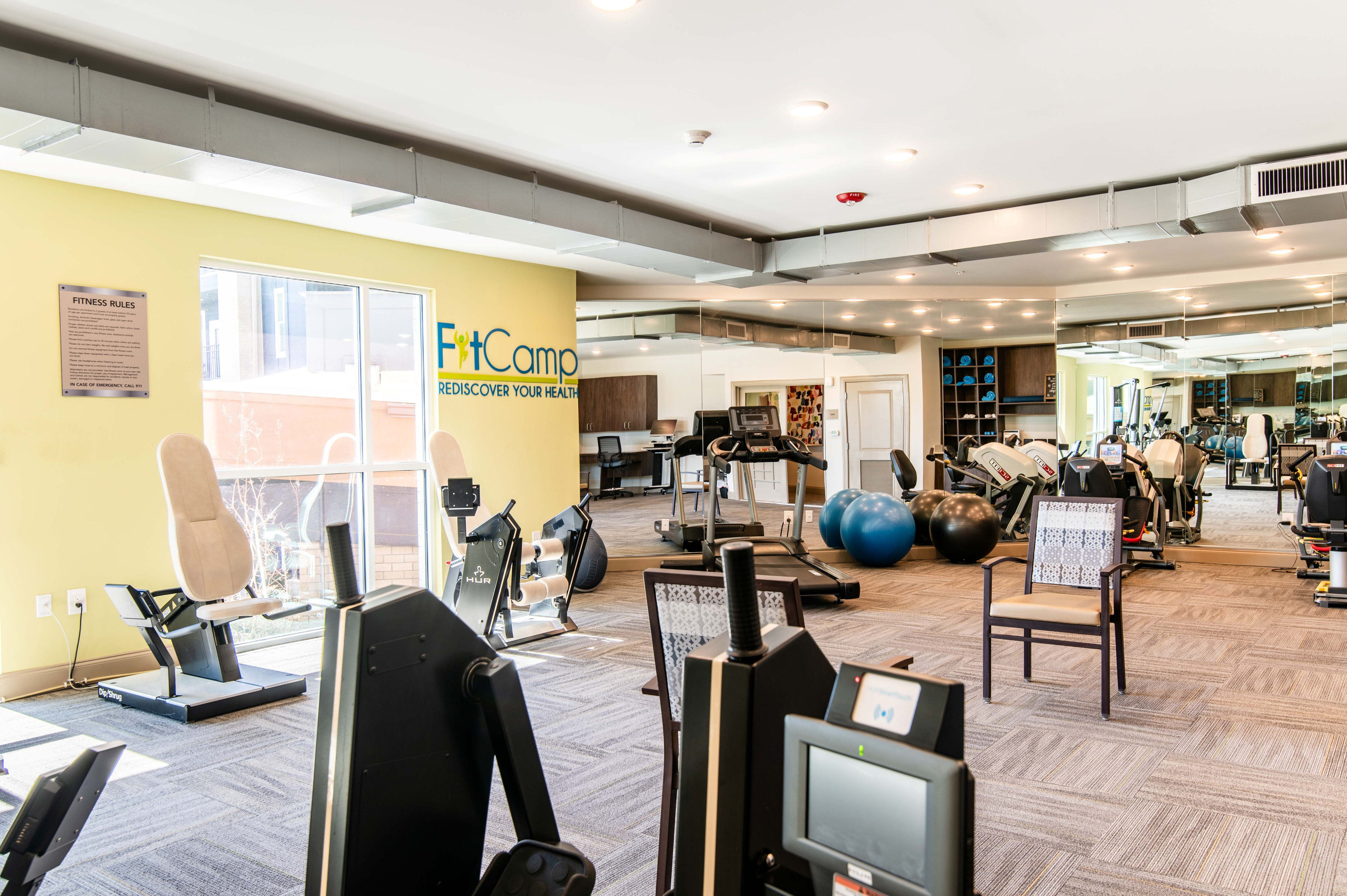 Modern fitness center featuring state-of-the-art exercise equipment, mirrored walls, and vibrant decor. Experience FitCamp\'s dynamic environment to revitalize your health journey.