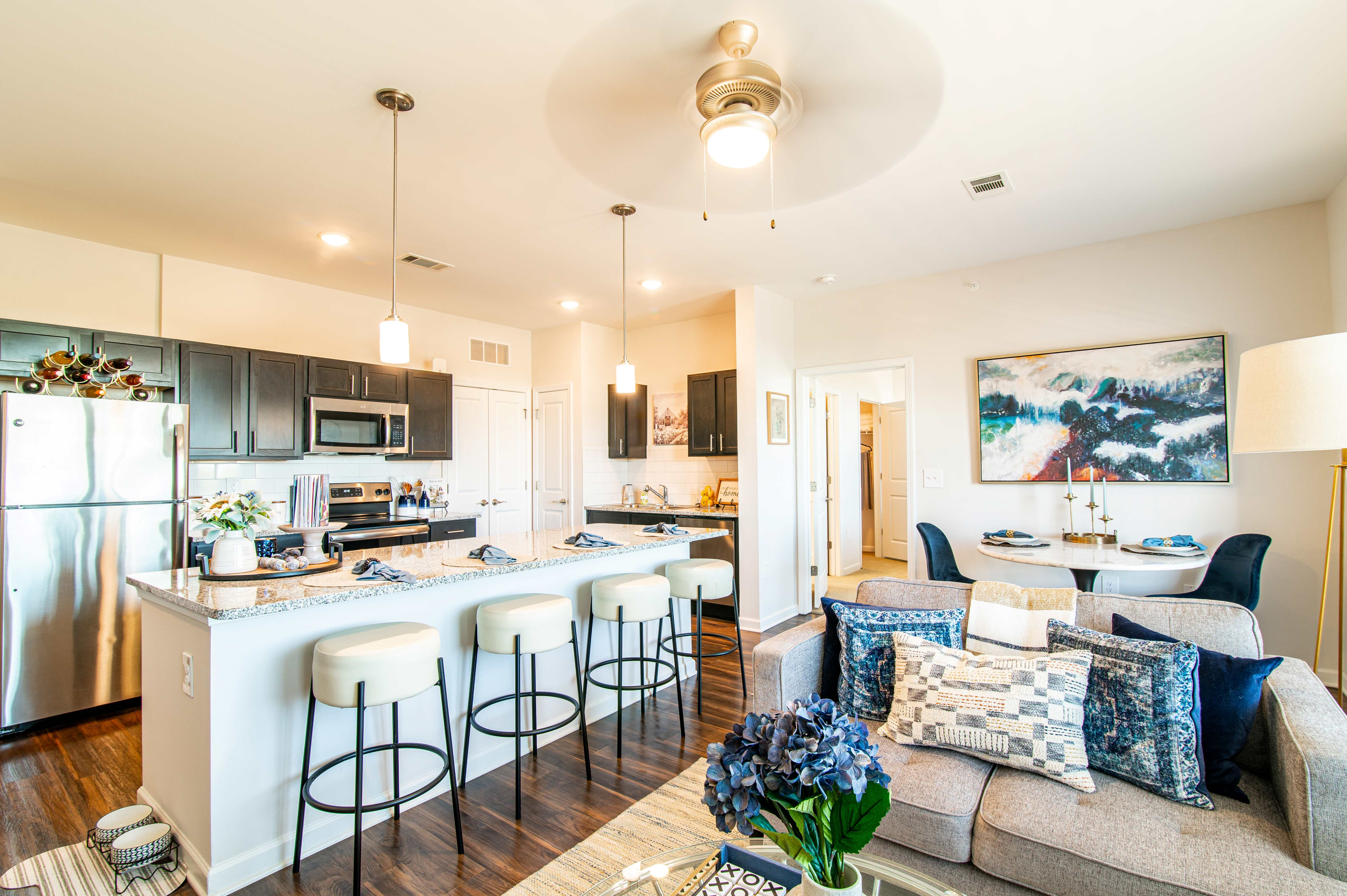 Elegant open-plan kitchen and living area featuring modern appliances, stylish bar seating, and a cozy dining nook.