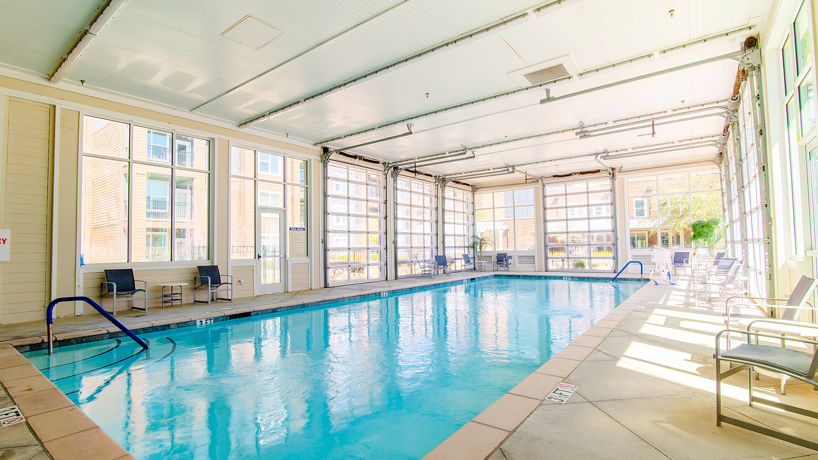 Bright and inviting indoor pool area with sunlit glass walls, perfect for relaxation and leisure.