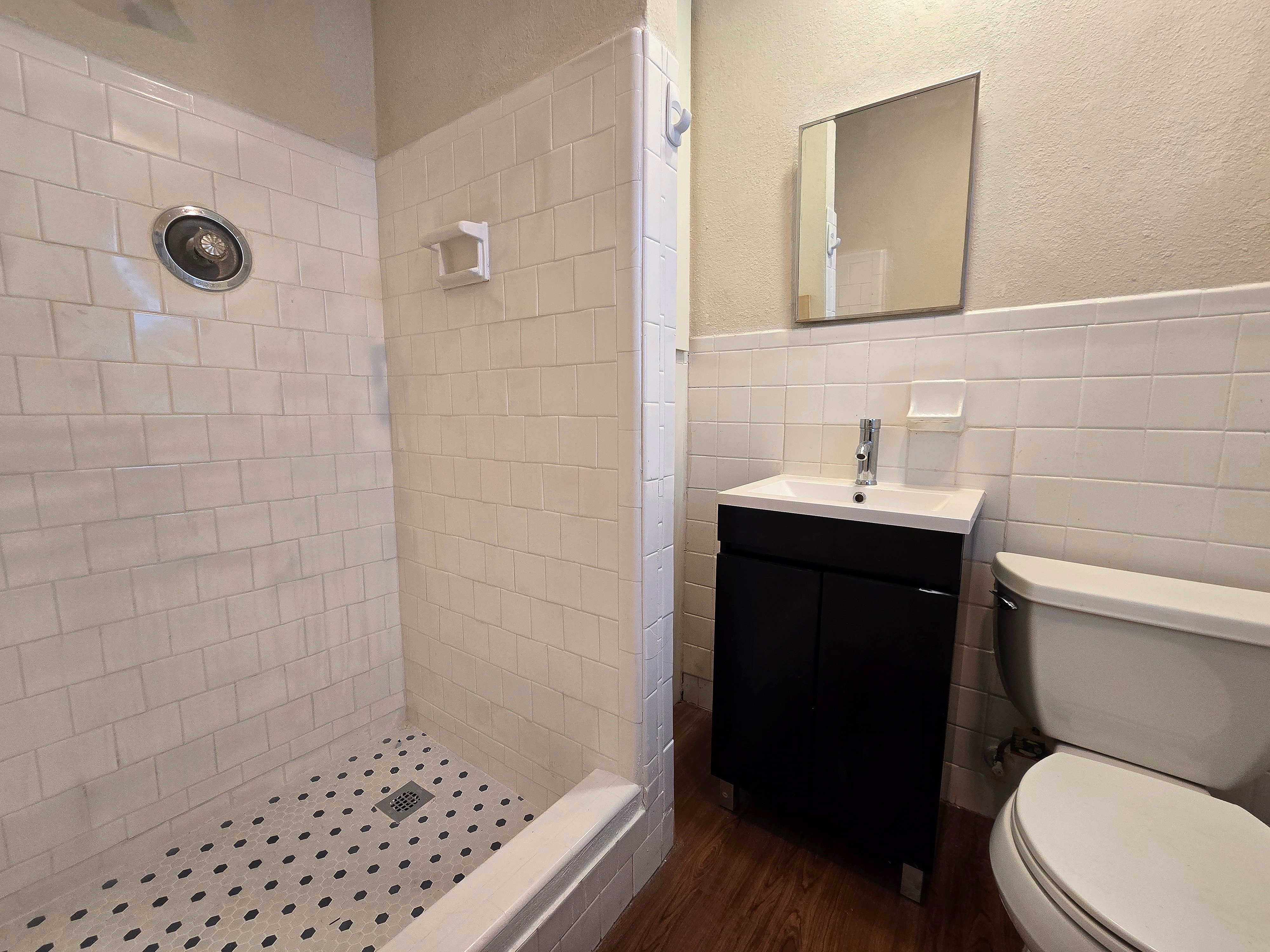 Modern bathroom featuring an elegant walk-in shower, sleek white tiles, and a stylish vanity.