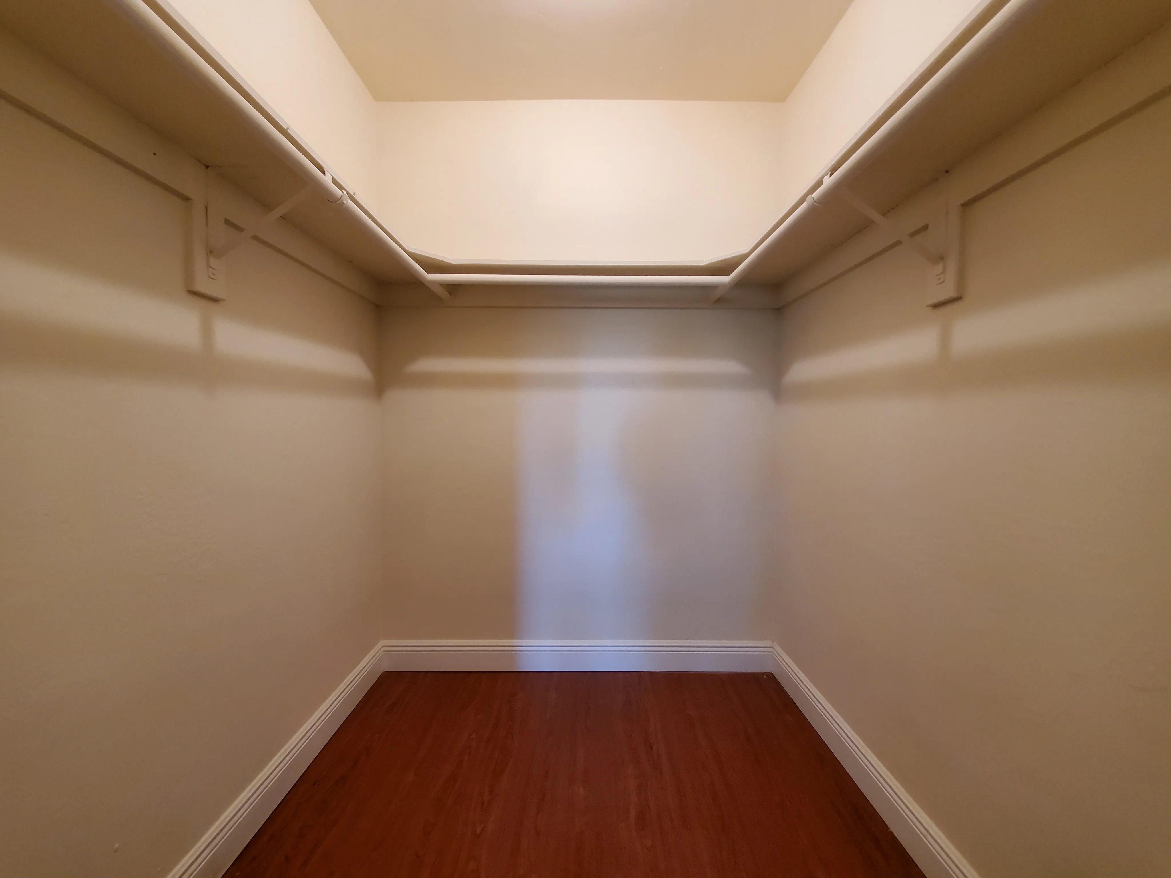 Spacious walk-in closet with ample shelving and elegant wood flooring, perfect for organizing clothes and accessories.