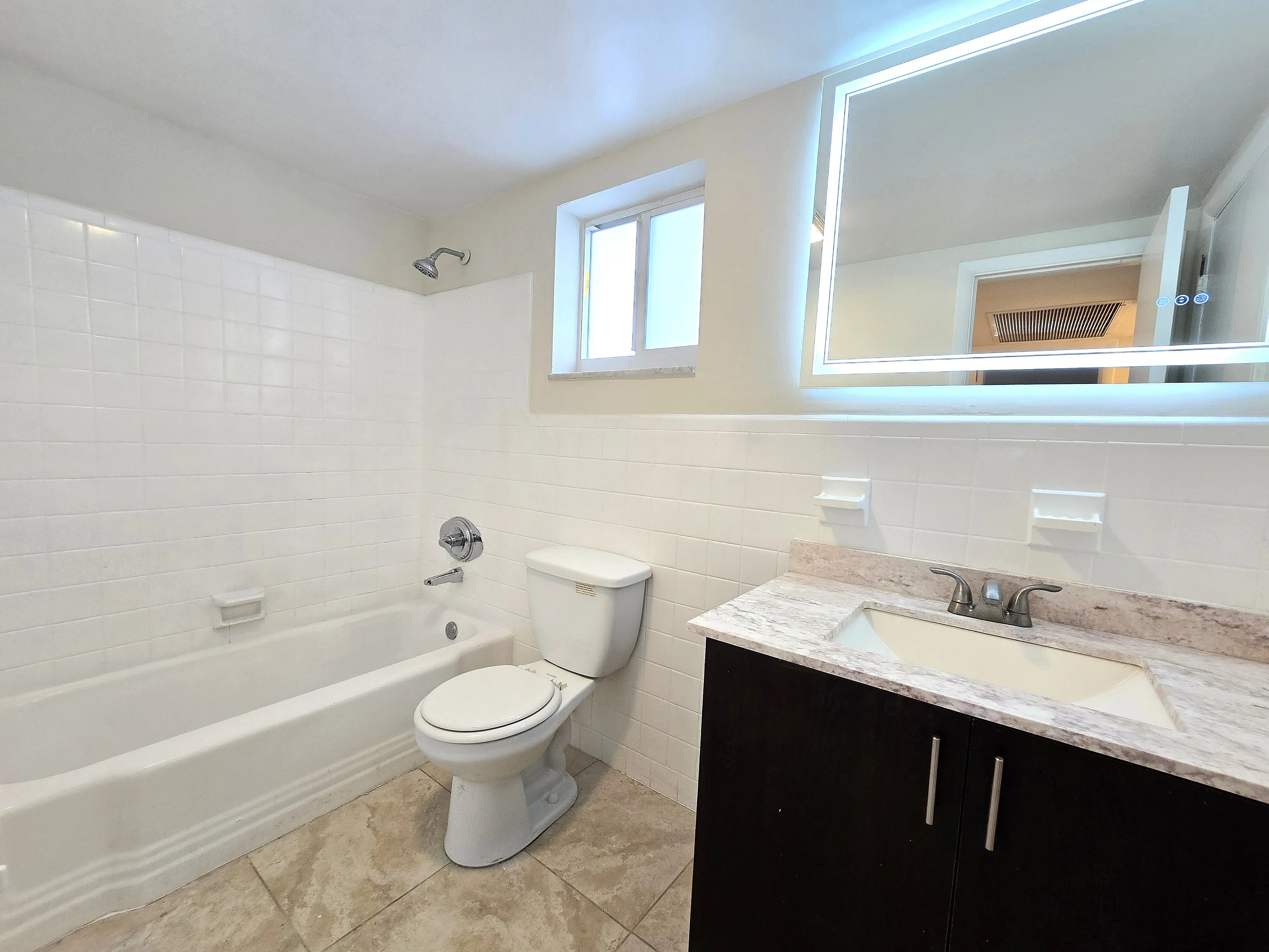 Bright, modern bathroom with elegant marble countertop, sleek mirror lighting, and contemporary fixtures.