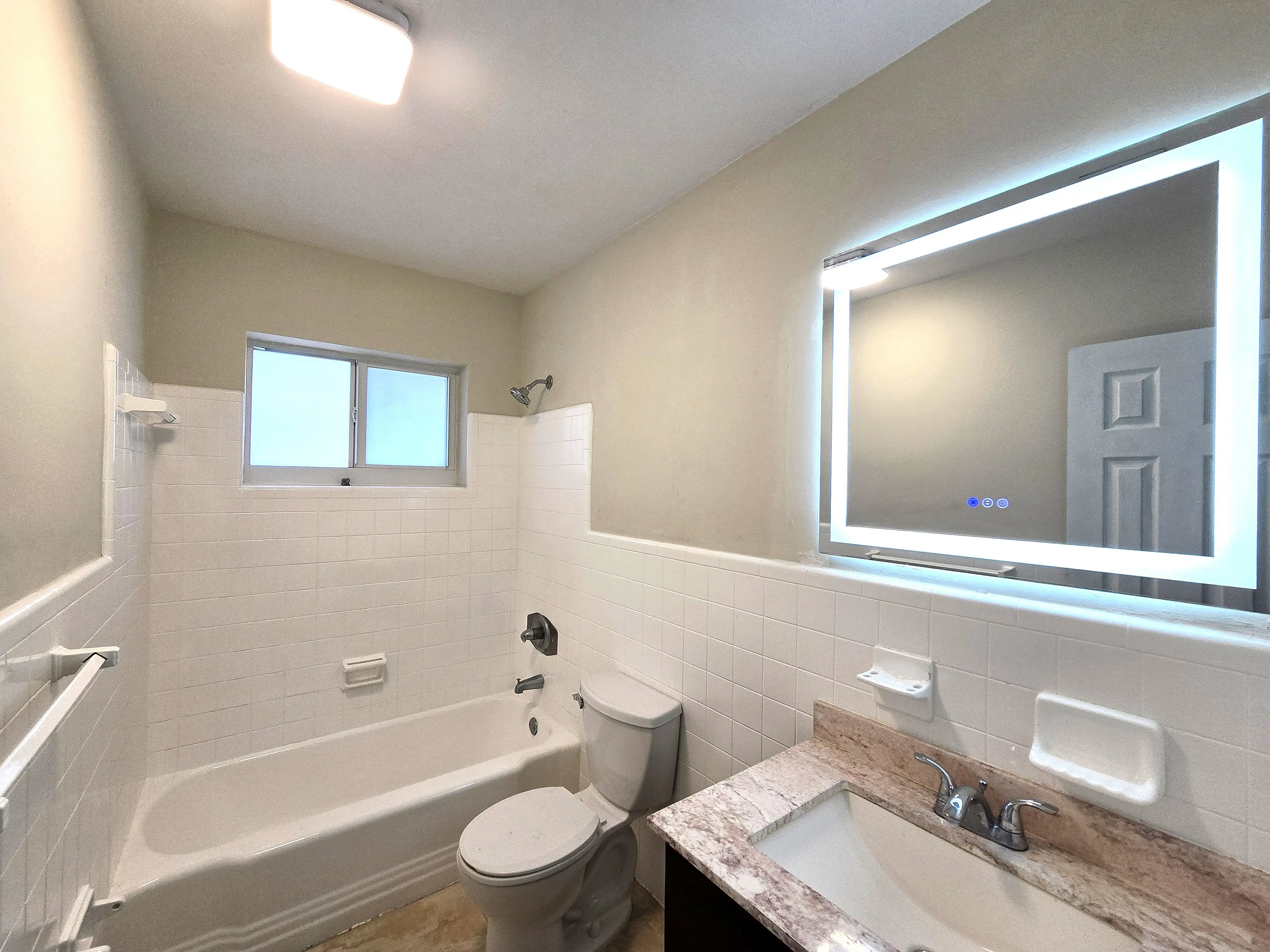 Elegant bathroom with modern LED mirror, classic white bathtub, and stylish fixtures for a luxurious living experience.