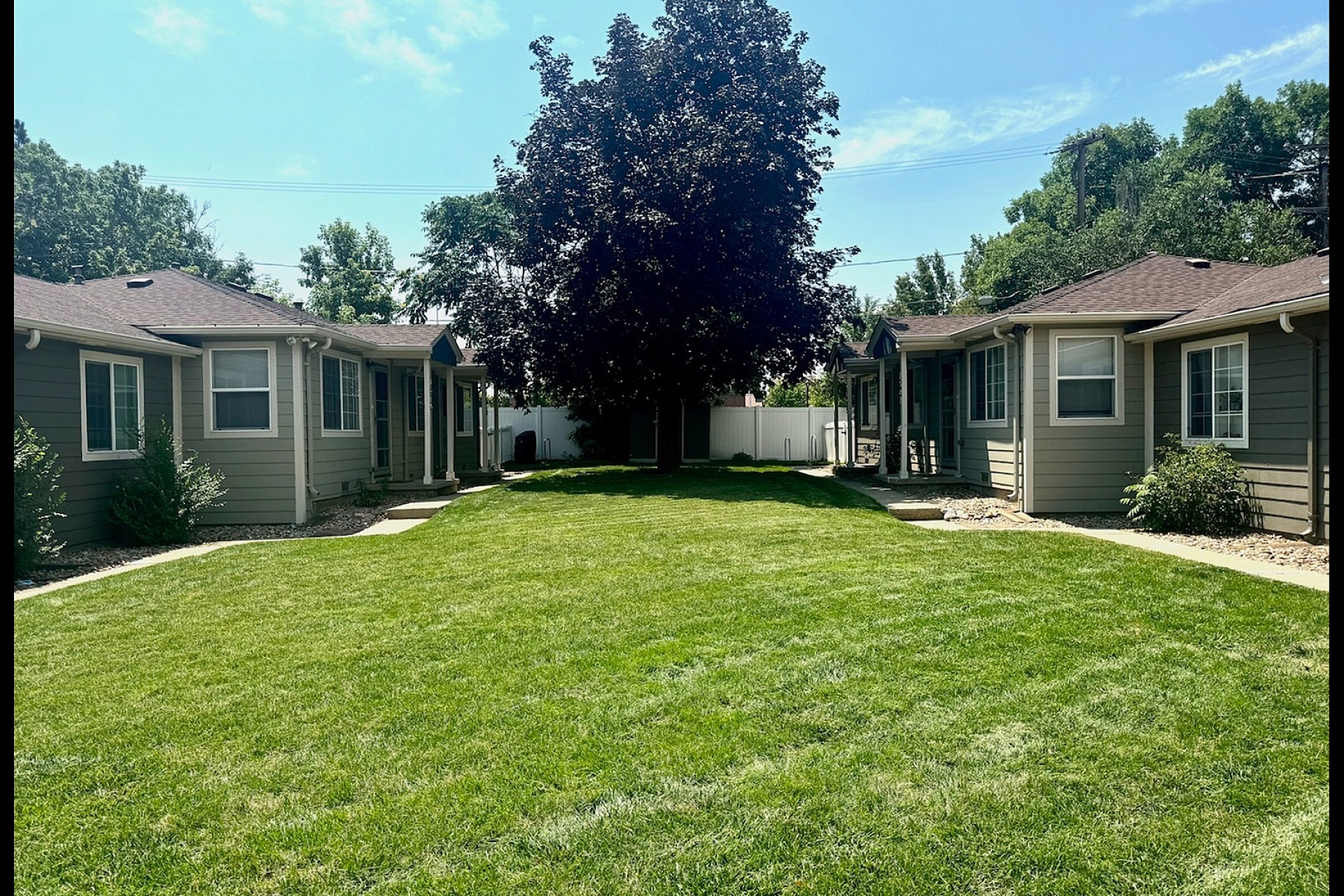 Charming apartment complex with lush green lawns, mature trees, and cozy units perfect for serene living.