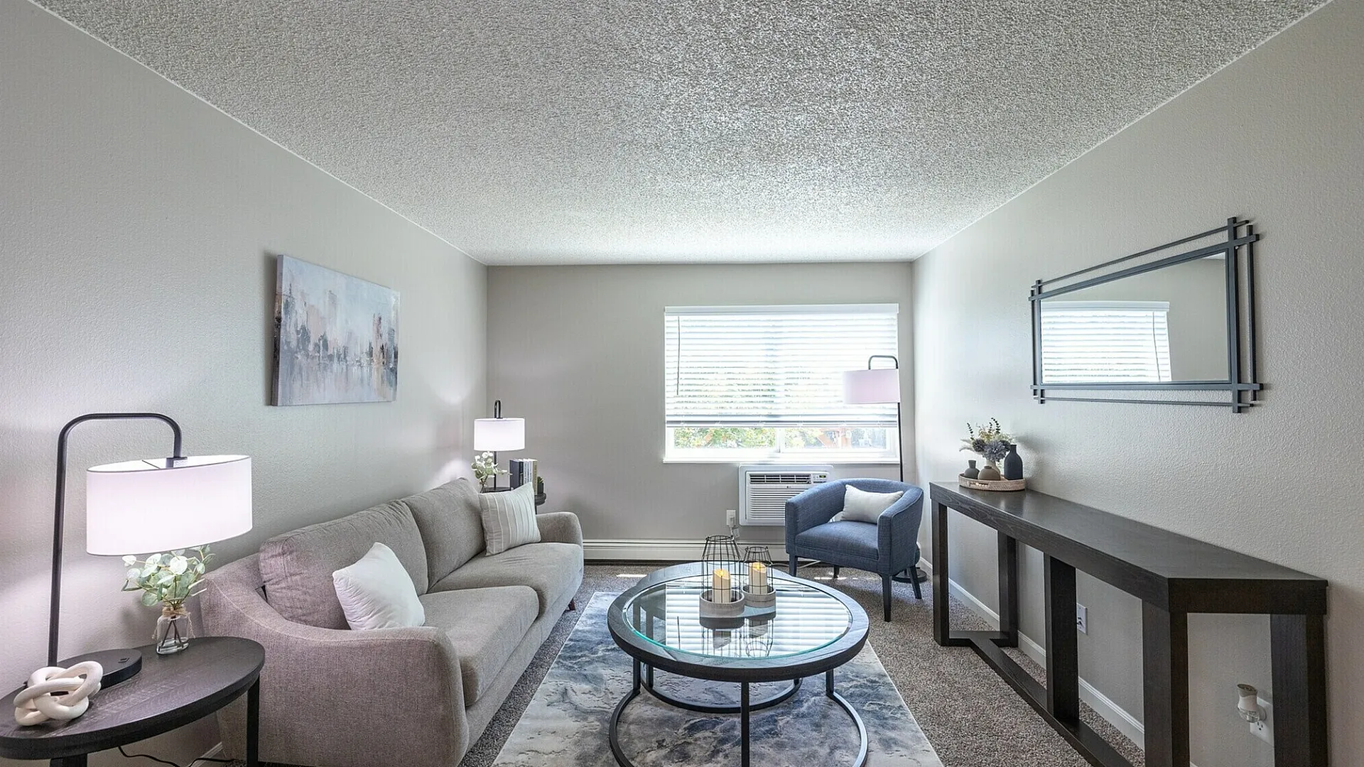 Modern living room with cozy gray sofa, stylish coffee table, chic decor, and abundant natural light.