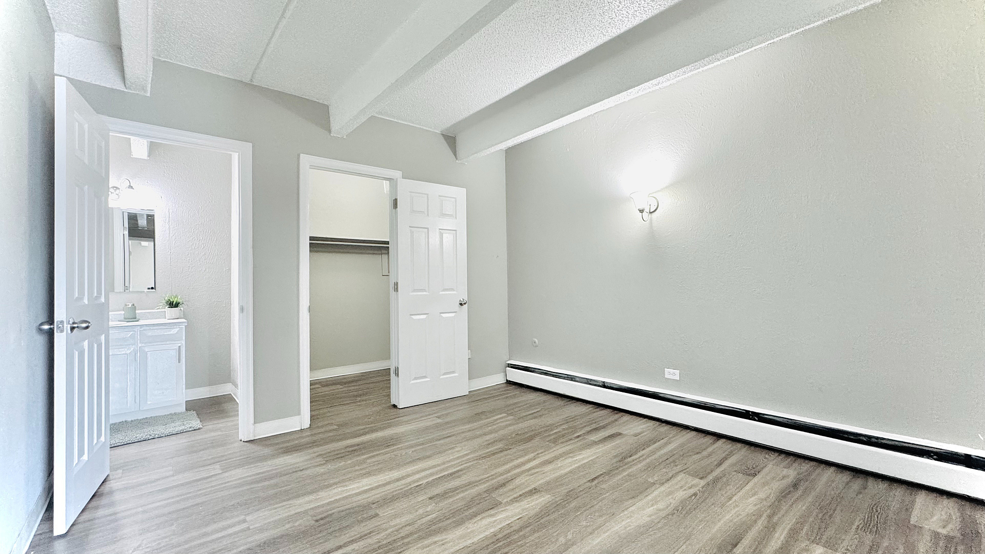 Bright and spacious bedroom with elegant wooden flooring, featuring a modern en-suite bathroom and ample closet space.