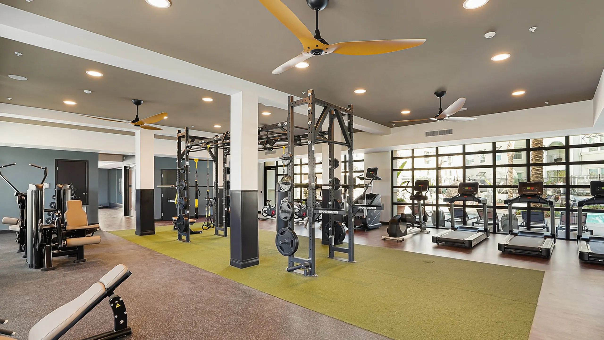Spacious, well-lit gym with modern fitness equipment, offering a perfect workout environment with natural light and stylish design.