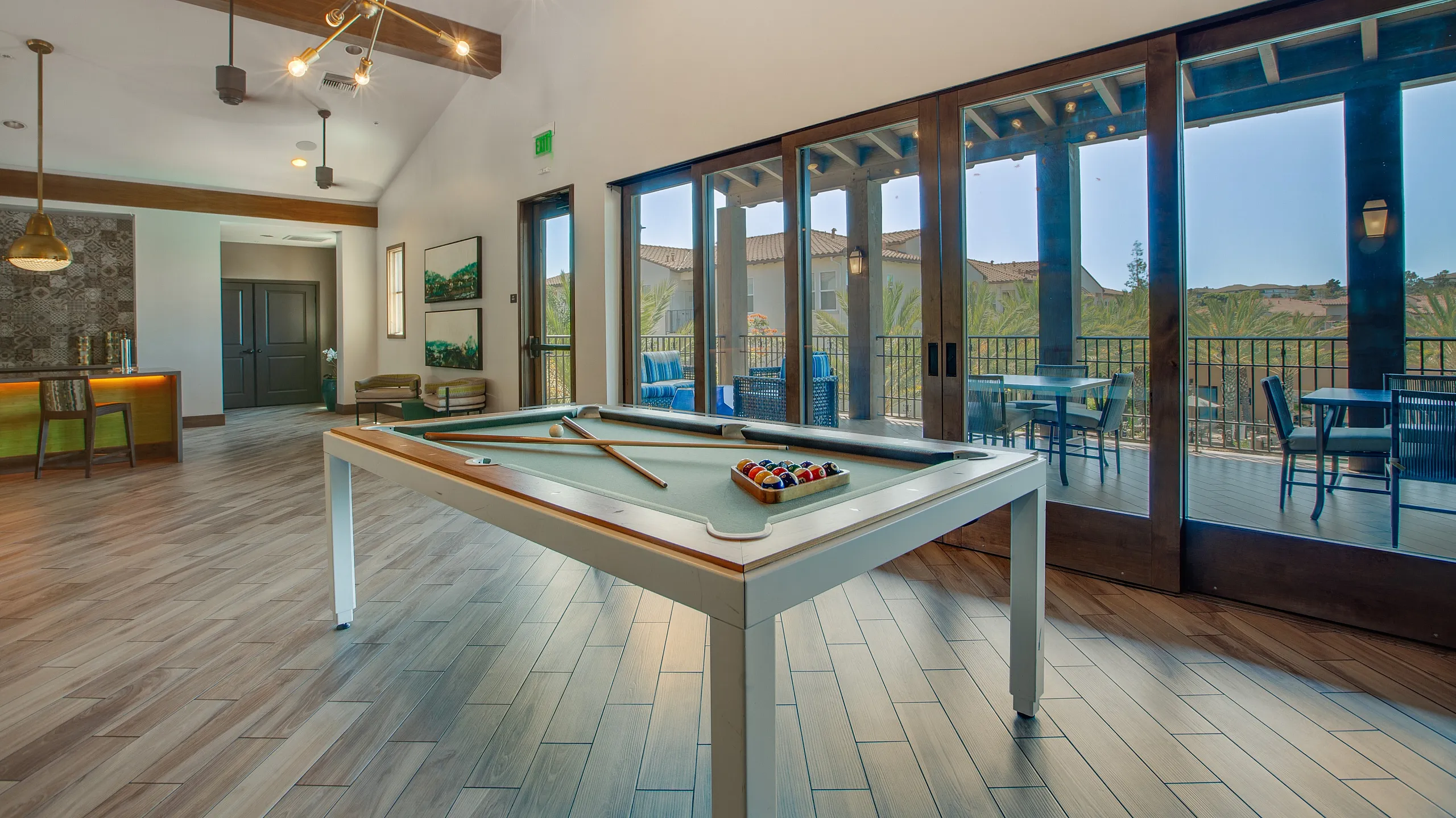 Luxurious recreation room featuring a modern billiards table, elegant lighting fixtures, and a spacious balcony with stunning views.