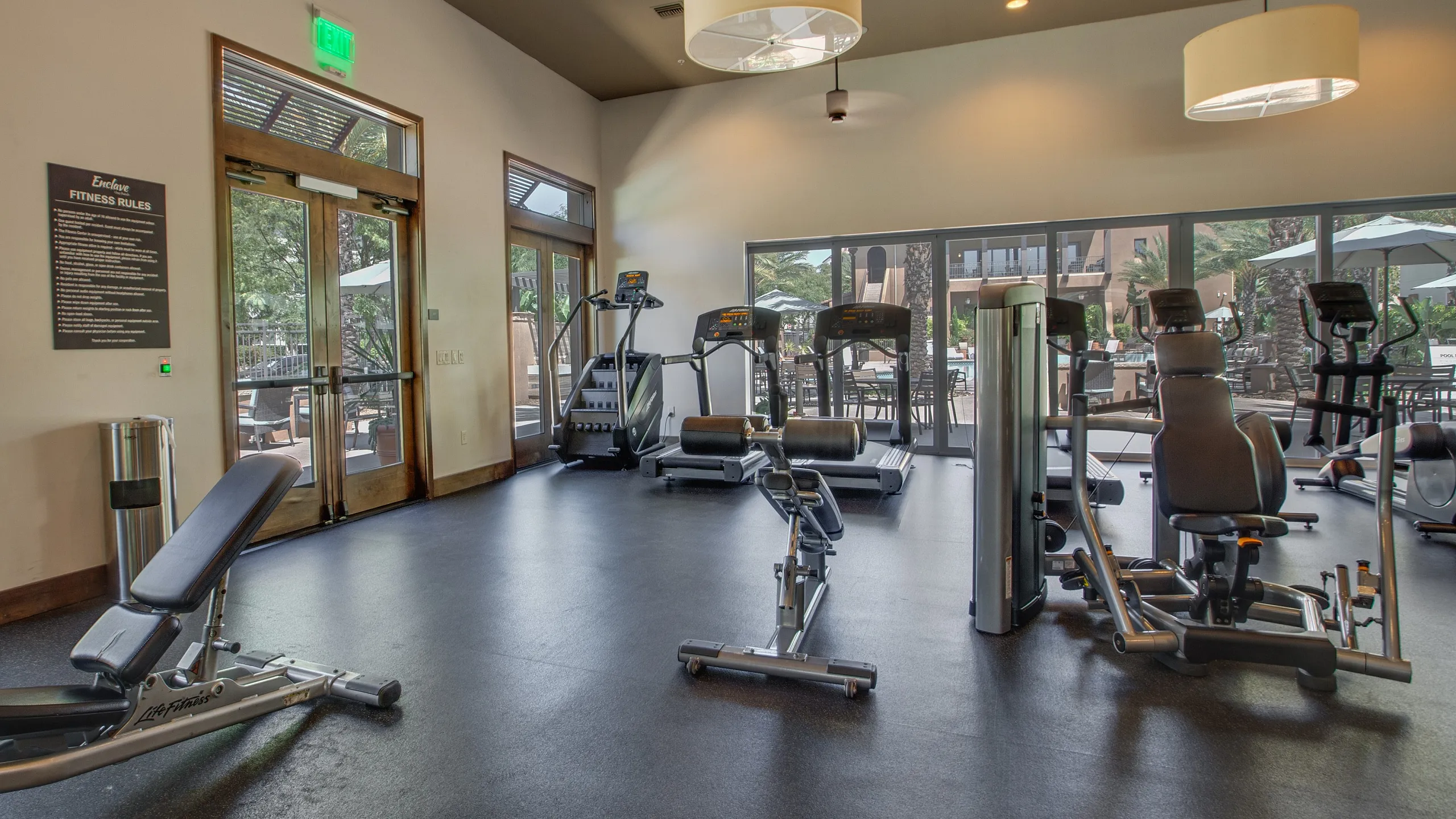 Modern apartment gym featuring state-of-the-art exercise equipment, including treadmills and weight machines, with abundant natural light.