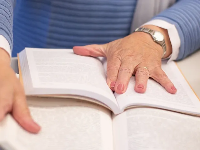 Close-up of a person reading a book, focusing on an engaging story in a cozy and calm setting.