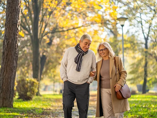 Joyful couple enjoying a romantic picnic under a tree, with a glass of wine and a basket, set in a tranquil park setting.