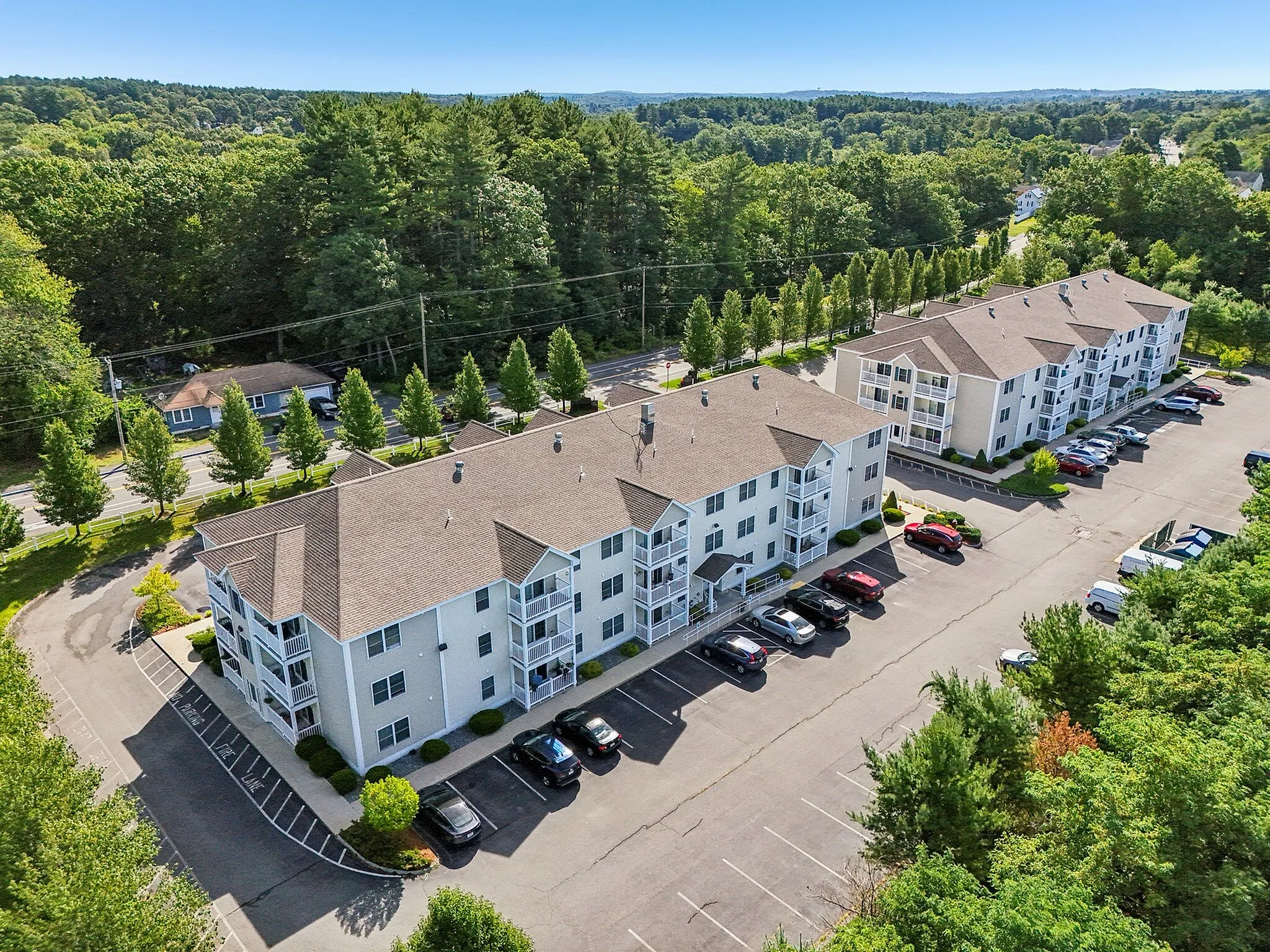 Charming apartment complex surrounded by lush greenery, with ample parking and serene setting.