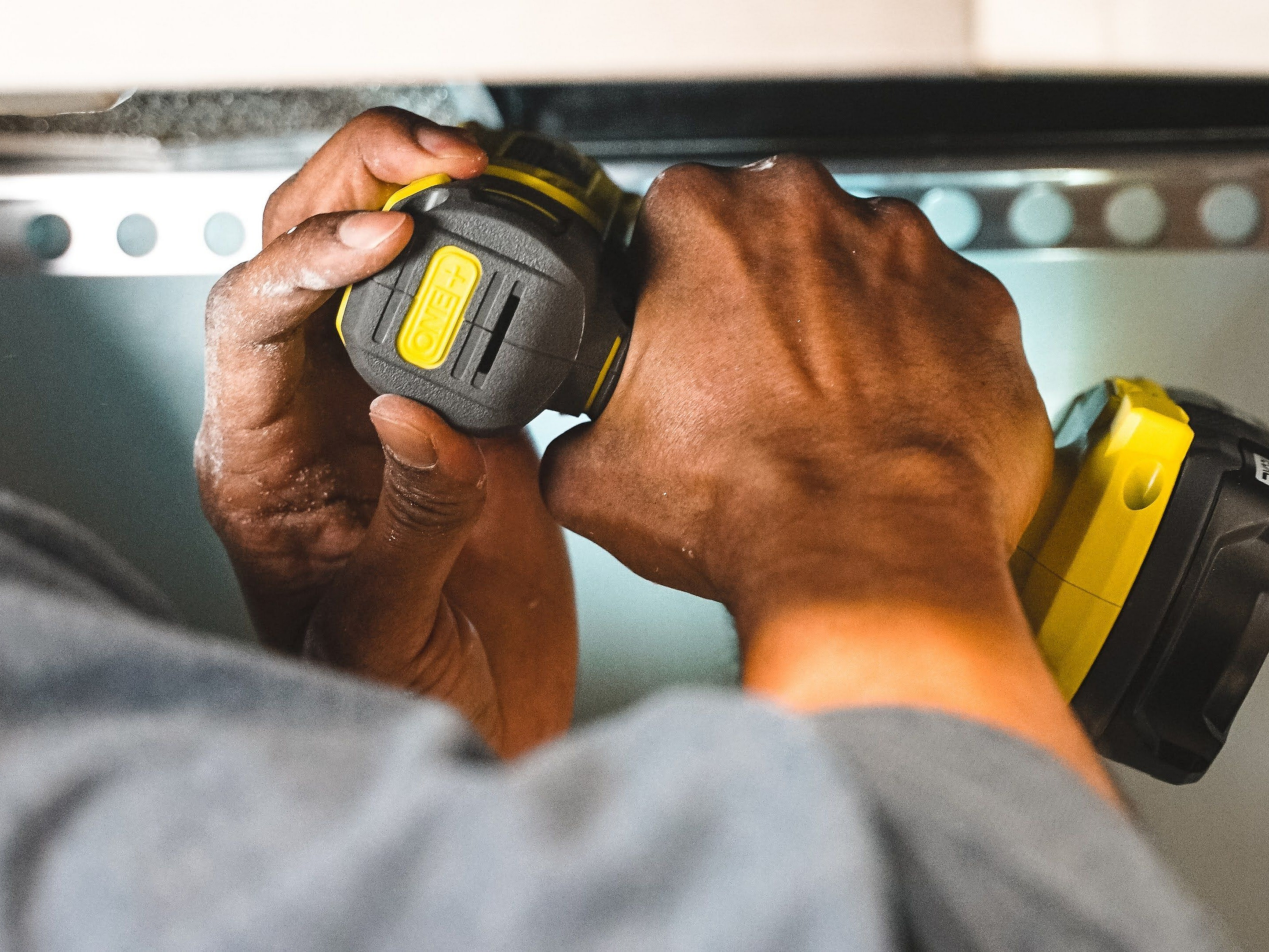 Close-up of skilled hands using a modern power tool, showcasing precision and craftsmanship in home improvement.