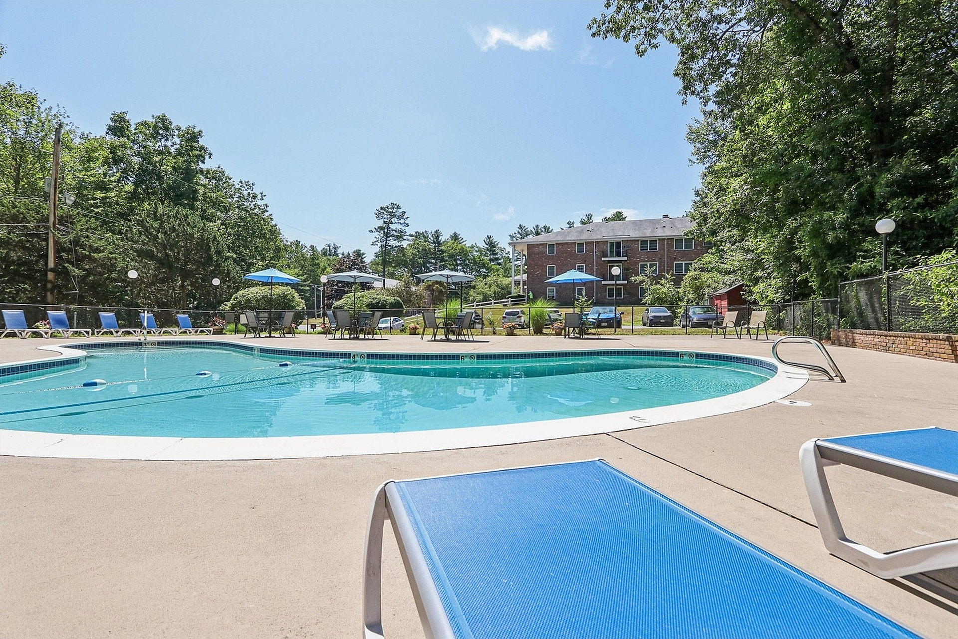 Inviting outdoor swimming pool area with sun loungers, nestled by lush greenery, perfect for relaxation and leisure.