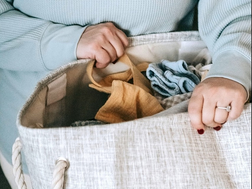 Cozy scene with a person holding a chic storage basket filled with colorful folded textiles.