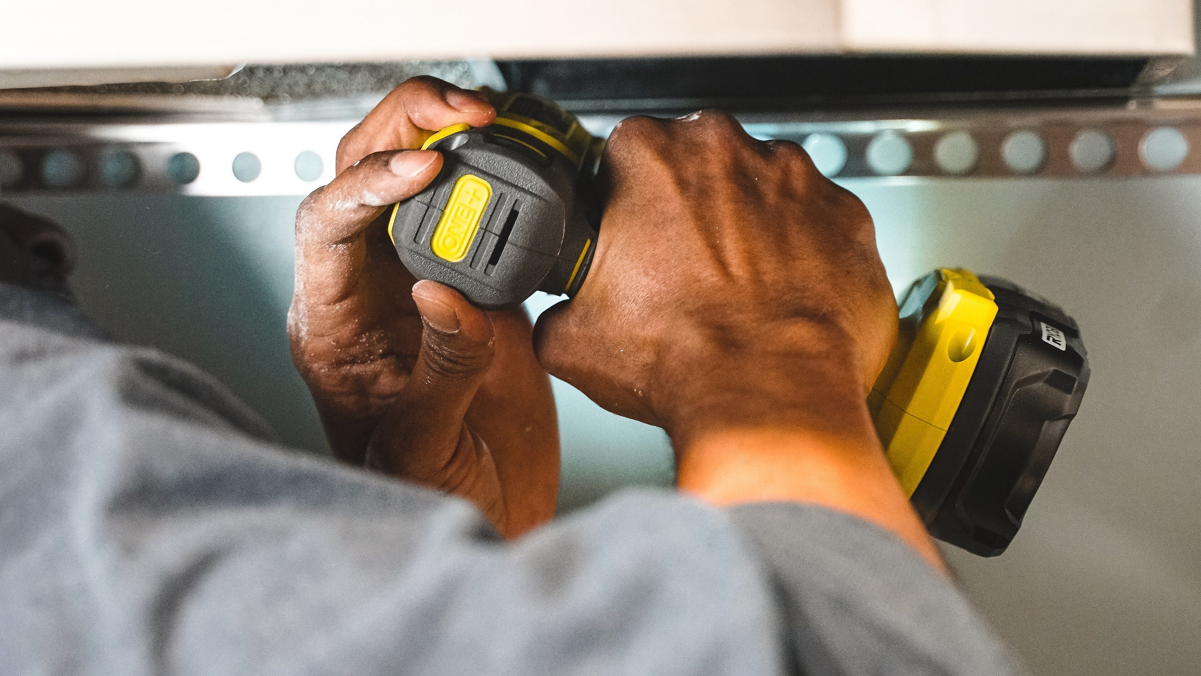 Close-up of hands using a yellow power drill for home improvement, highlighting craftsmanship and precision.