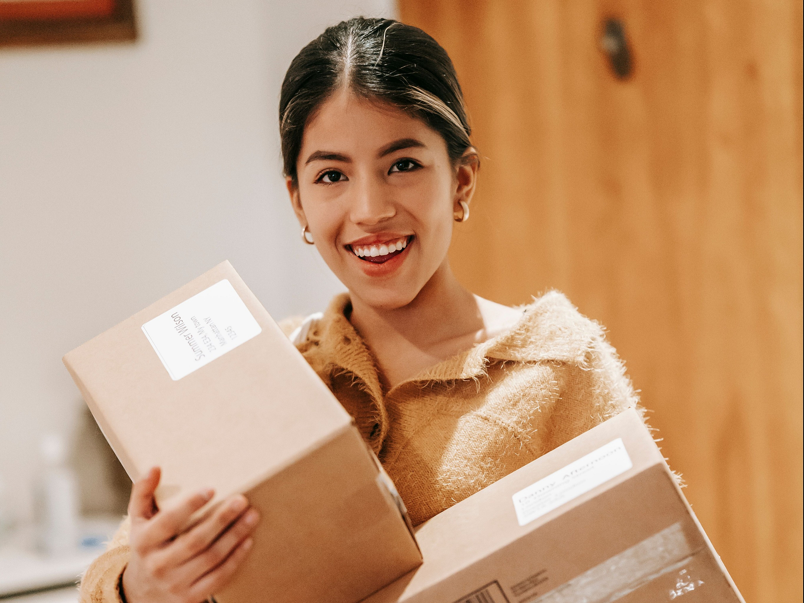 Cheerful person carrying packages inside a cozy apartment, showcasing a warm and inviting home environment.