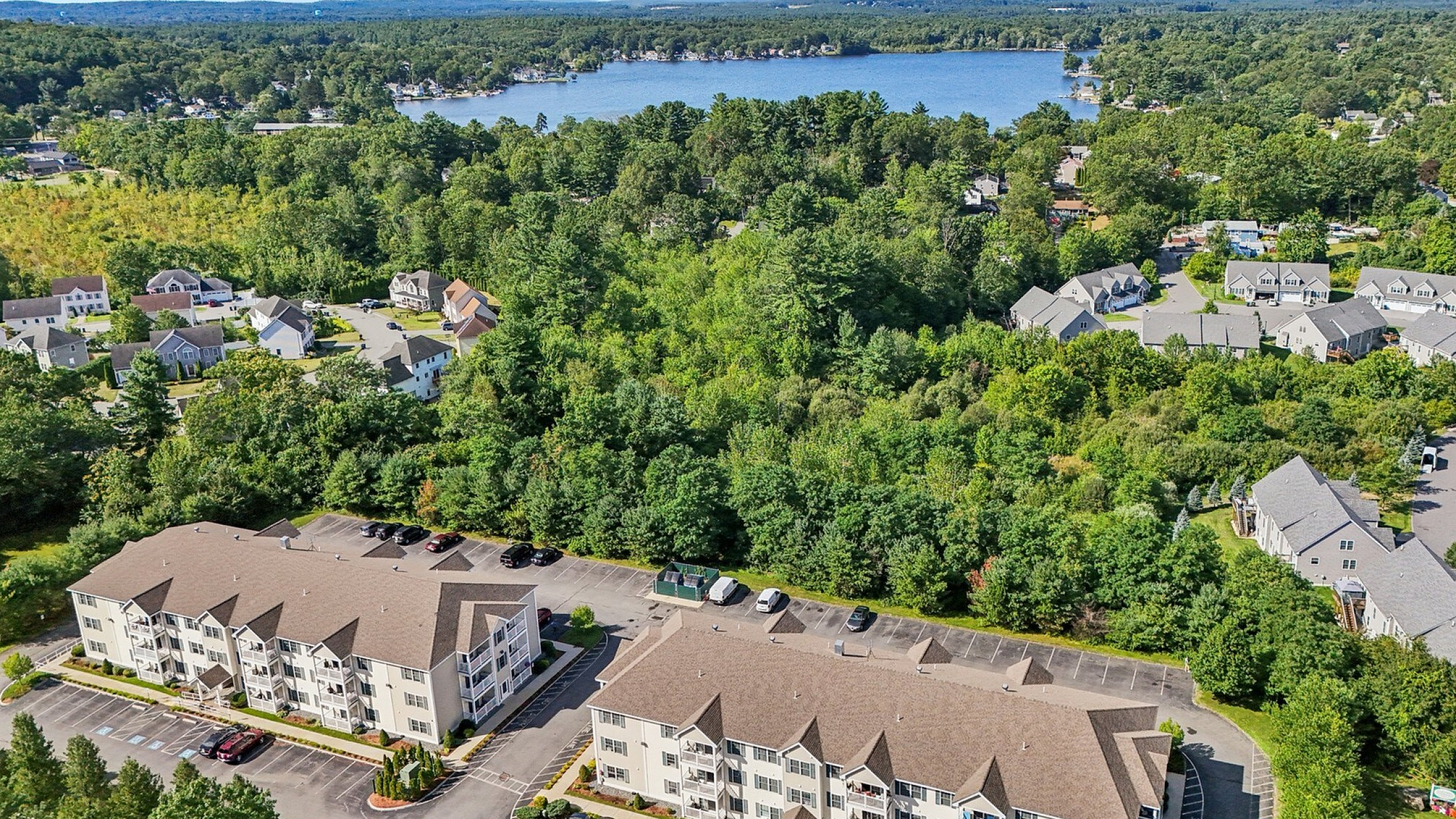 Charming apartment complex nestled amidst lush greenery with picturesque lake views, perfect for serene living.