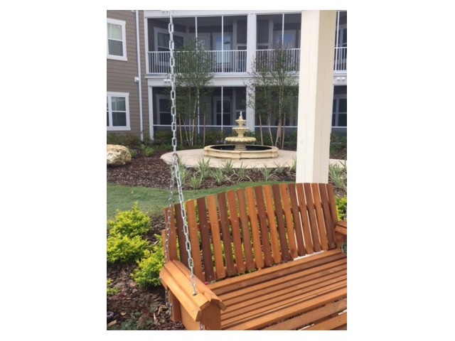 Zen courtyard with a large wooden swing, fountain, and green space l Monterey Pointe