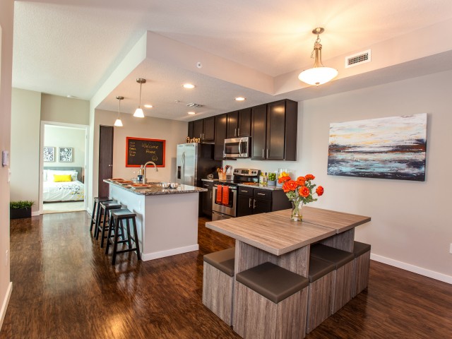 Model home interior of dining room, kitchen with island and seating and looking into the bedroom l High Ridge Landing