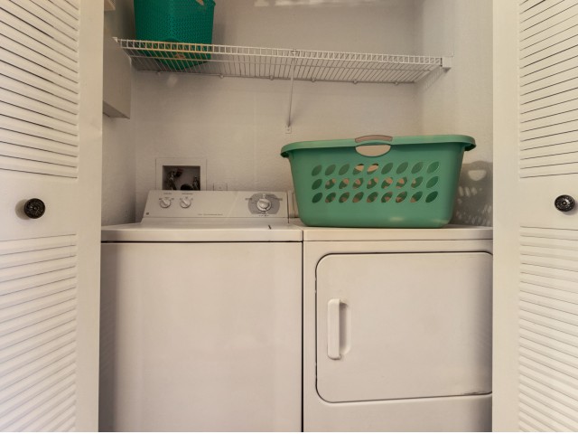 Apartment laundry room with a top loading washer, side loading dryer, and shelving above