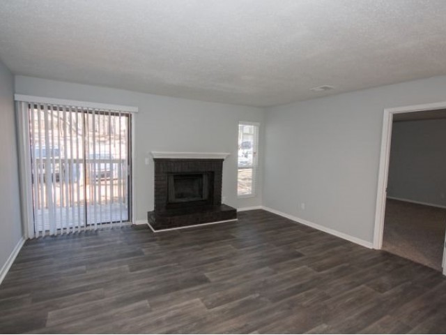 living room with grey painted walls and white trim, fireplace wood floors and vertical blinds to balcony