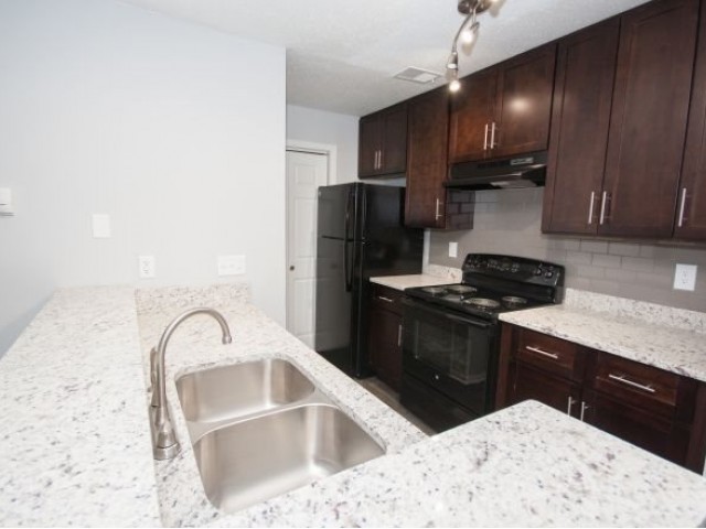 kitchen with white granite counters, black appliances with refrigerator and stove