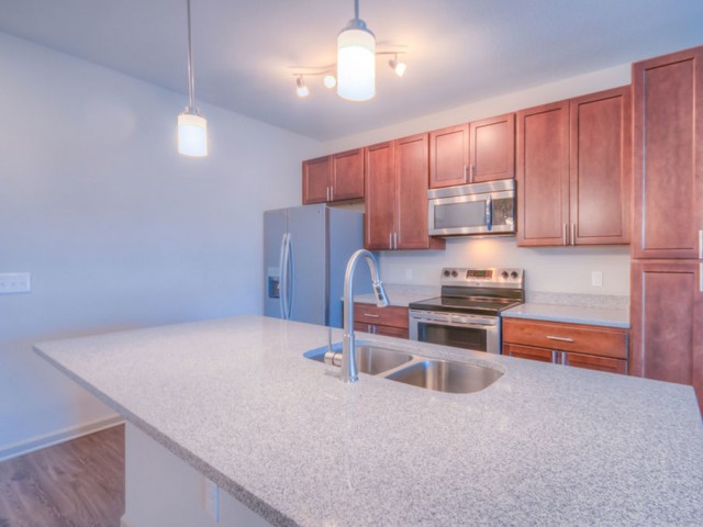 San Mateo Apartments Kissimmee  Florida island kitchen with wood cabinets, stainless steel appliances and granite countertops