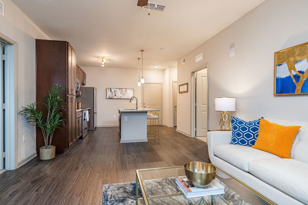 San Mateo Apartments Kissimmee Florida open living area adjacent to kitchen with vinyl plank flooring, wood cabinets, pendant lights, granite counters, and stainless appliances