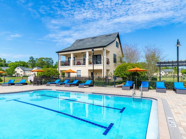 Park Lane Apartments in Gainesville pool adjacent to a residential building with lap markers in the pool and surrounded by trees