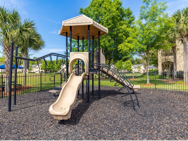 Park Lane Apartments in Gainesville fenced playground with mulch, monkey bards, slide and shading