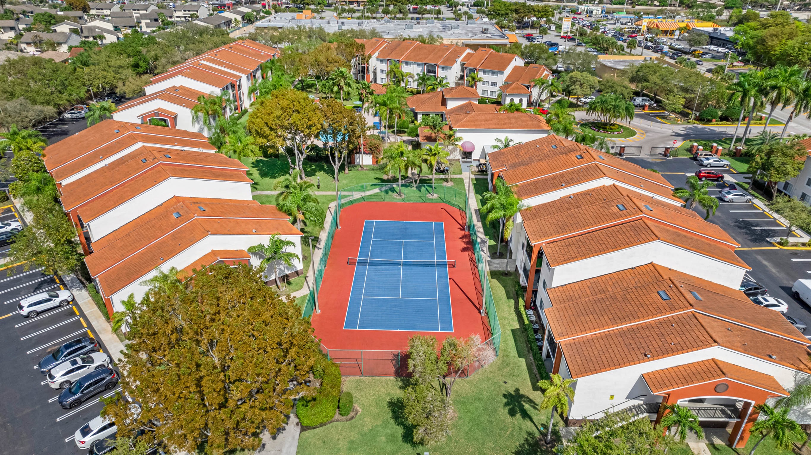 Panoramic view of community outdoor tennis court, fenced on all sides