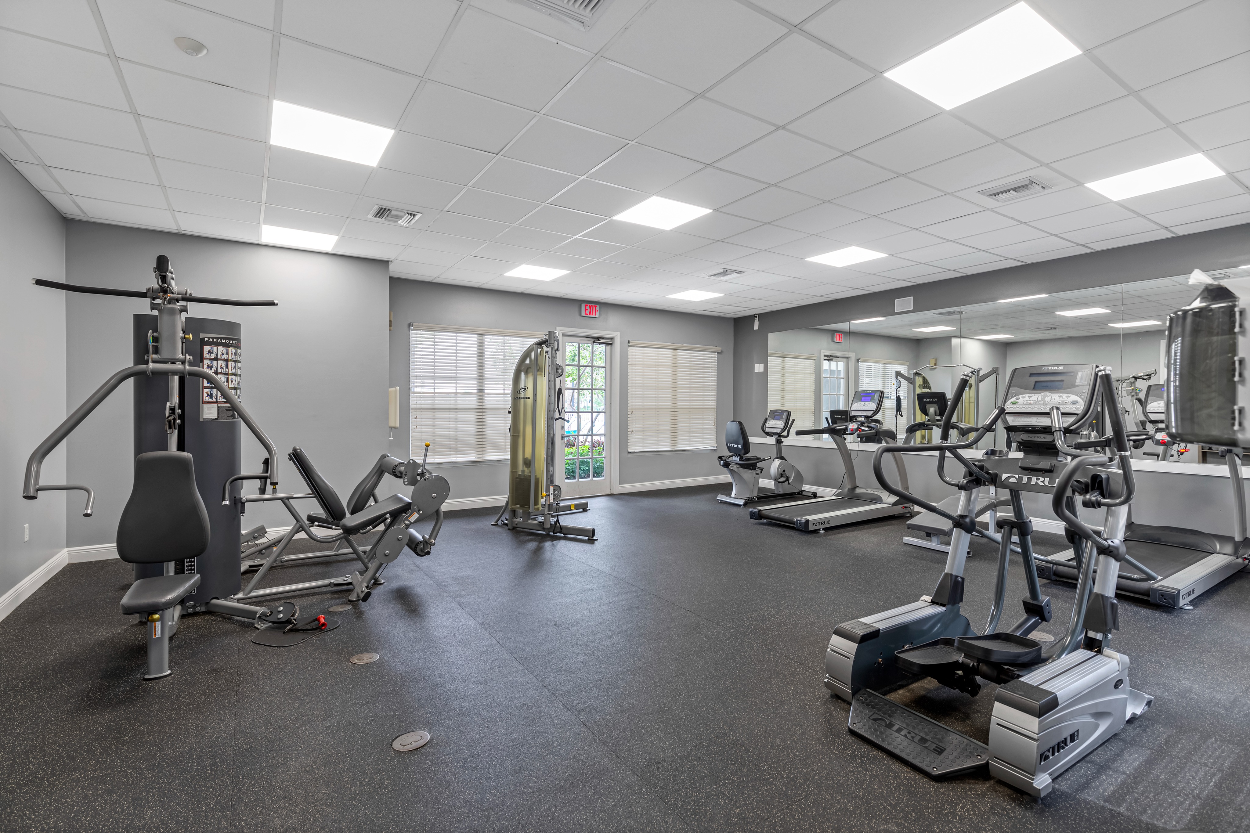 Fitness center with mirrored wall, treadmills, workout benches, and various weight machines