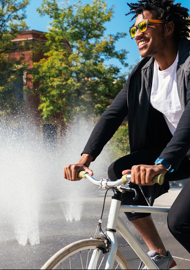 Man riding bicycle through sprinkler