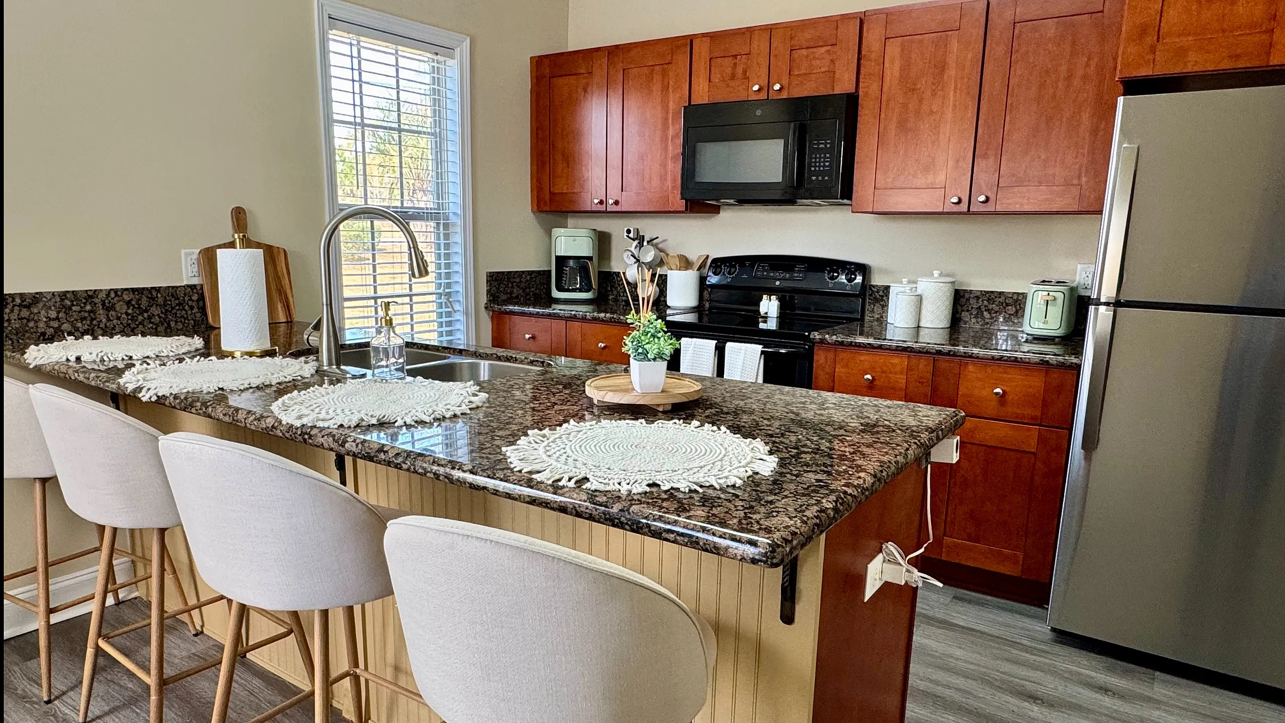 Contemporary kitchen with granite countertops, wooden cabinets, and a cozy breakfast bar with modern seating.