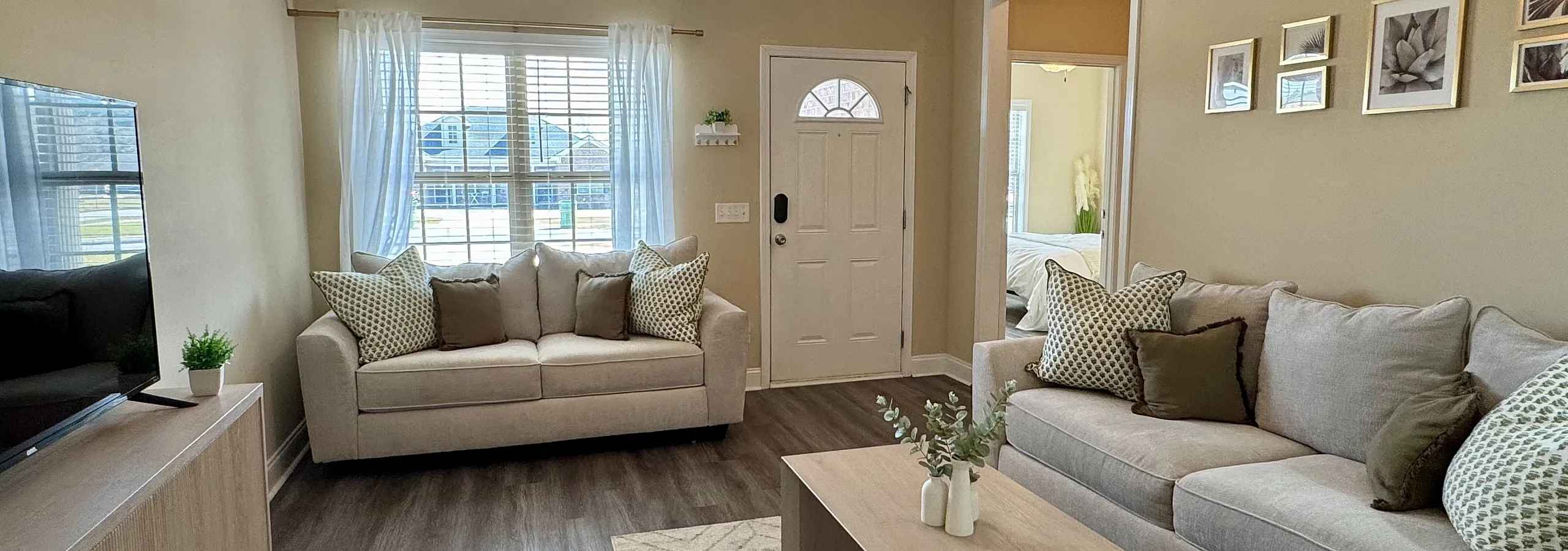 Stylish living room with modern decor, featuring plush sofas, a wooden coffee table, and a flat-screen TV.