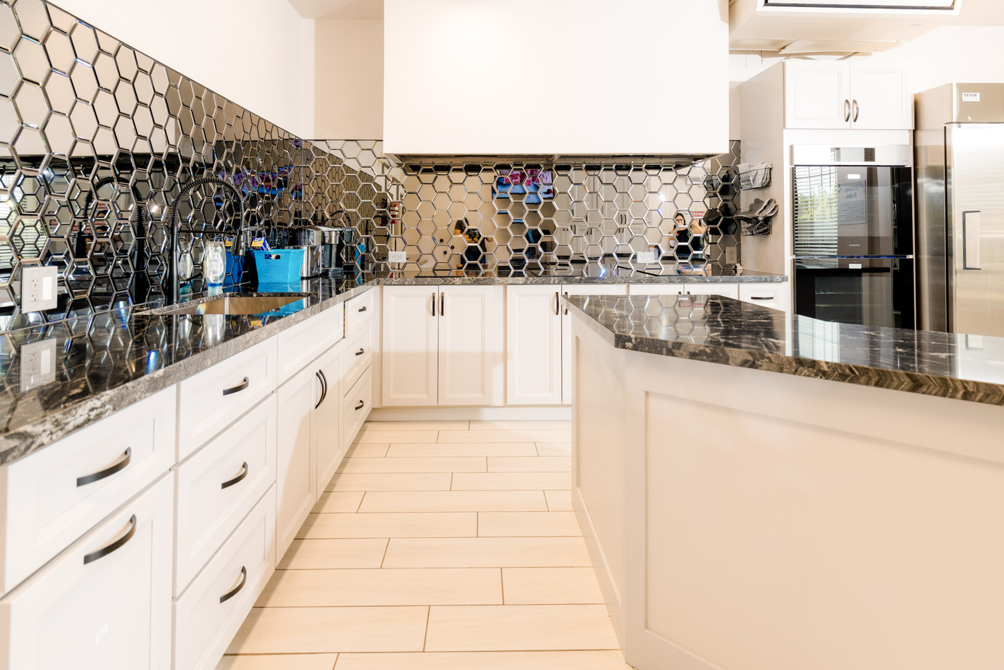 Sophisticated kitchen with sleek black granite countertops, modern honeycomb tile backsplash, and elegant white cabinetry.