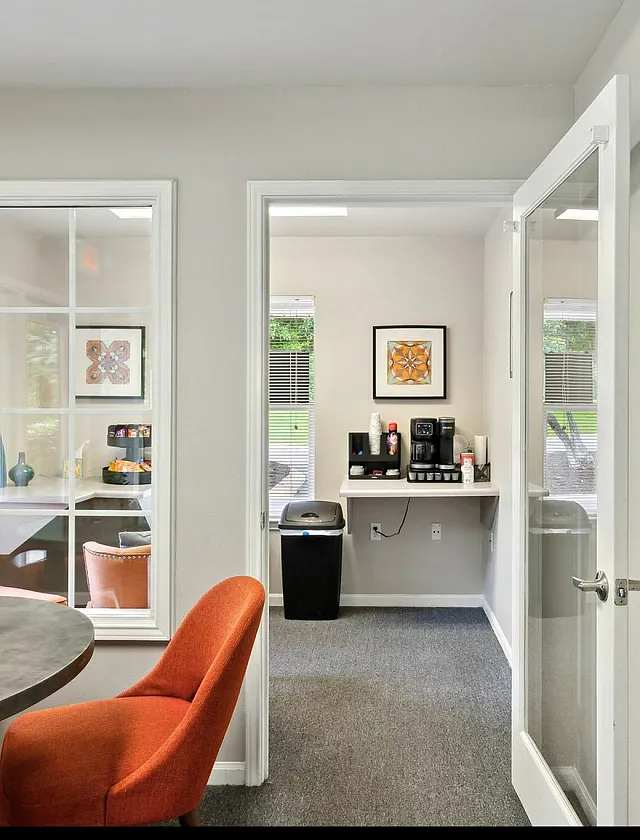 Inviting office space with a bright seating area, modern coffee station, and elegant decor.