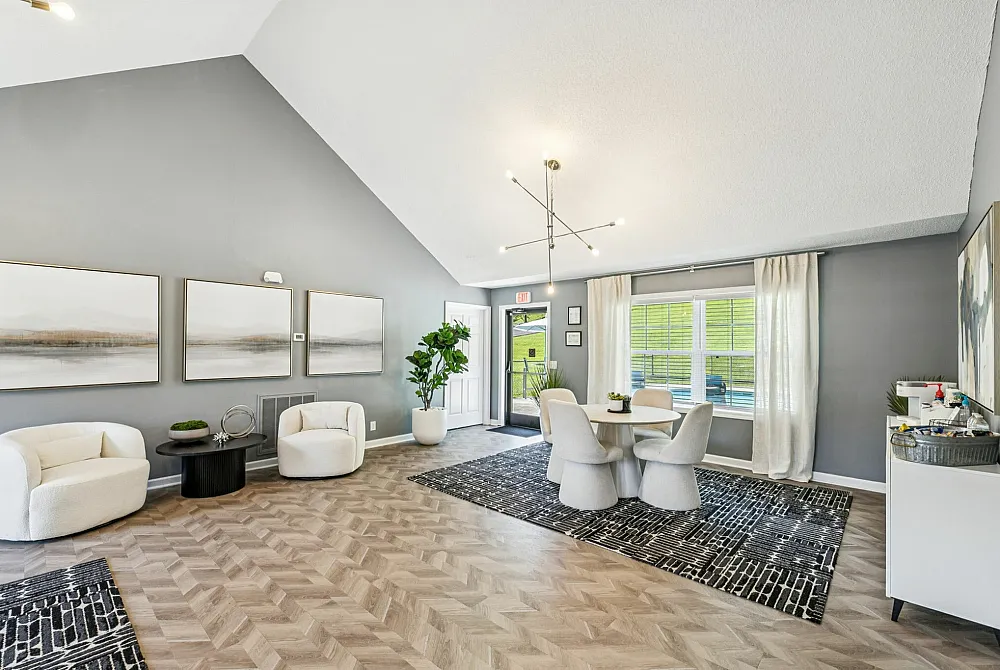 Elegant living space with modern decor, featuring cozy white chairs, abstract artwork, and a chic dining area bathed in natural light.